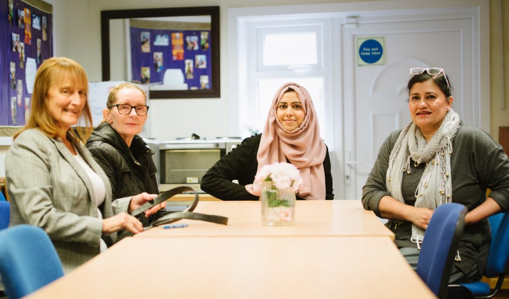 Four women sat around table at Lancashire Investors in Community