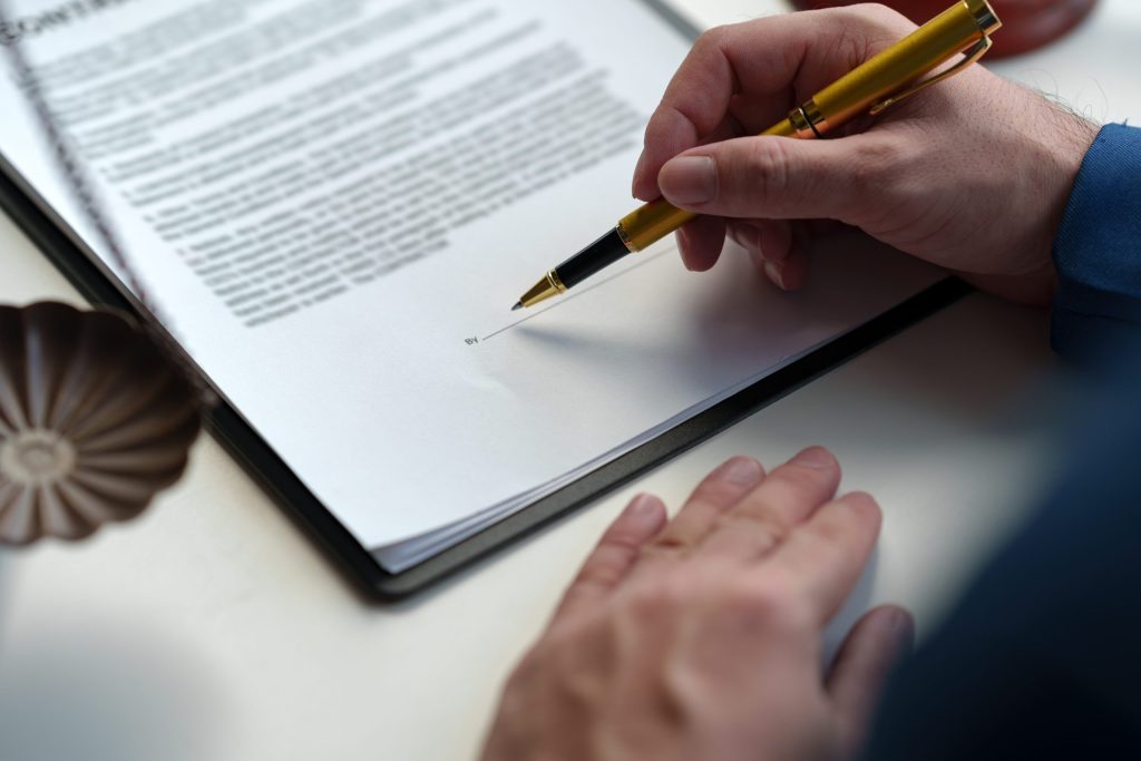 Image of someone signing a trust transfer with pen in hand