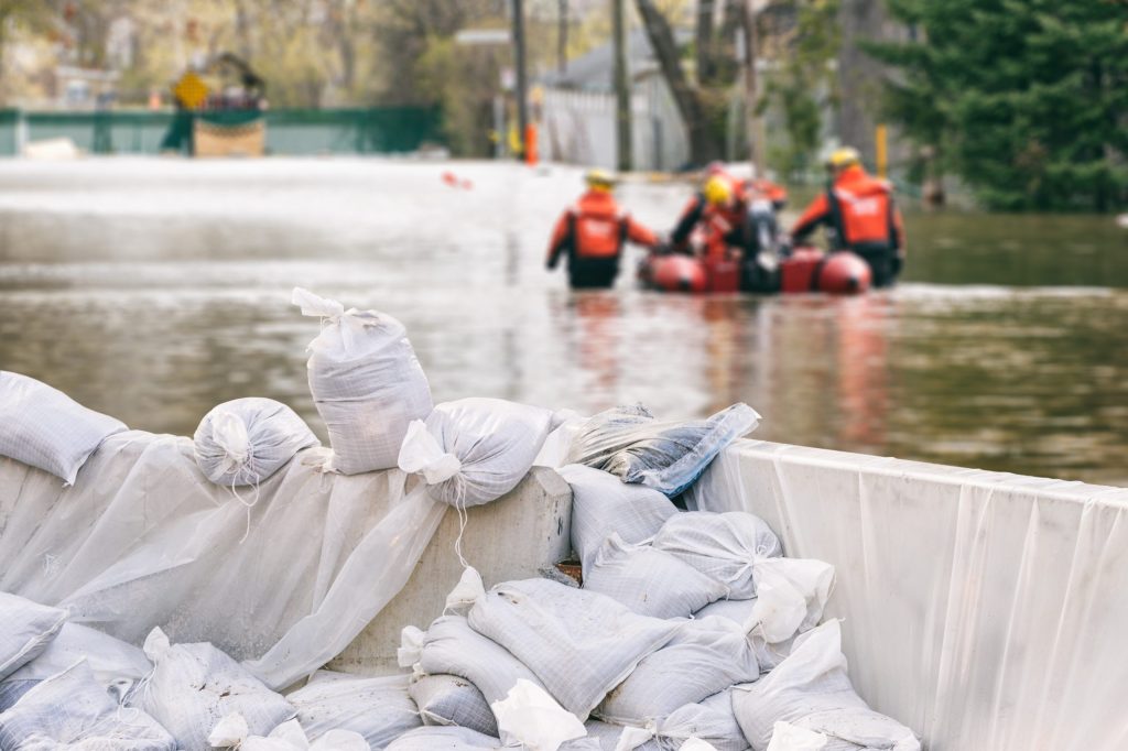 Flood,Protection,Sandbags,With,Flooded,Homes,In,The,Background,(montage)